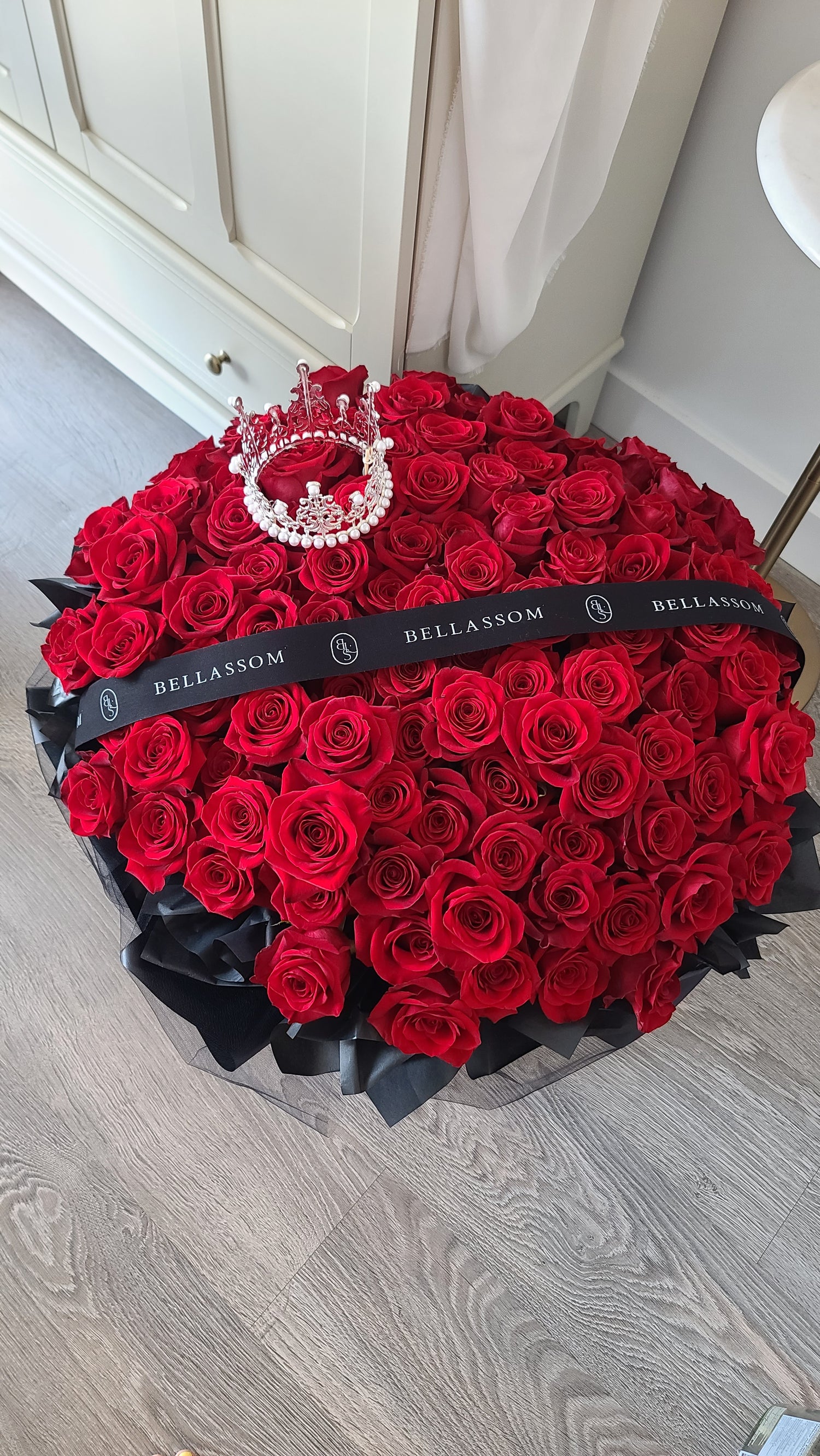 Close-up of a sparkling silver crown nestled on top of 100 premium red roses. Delivery rose in vancouver