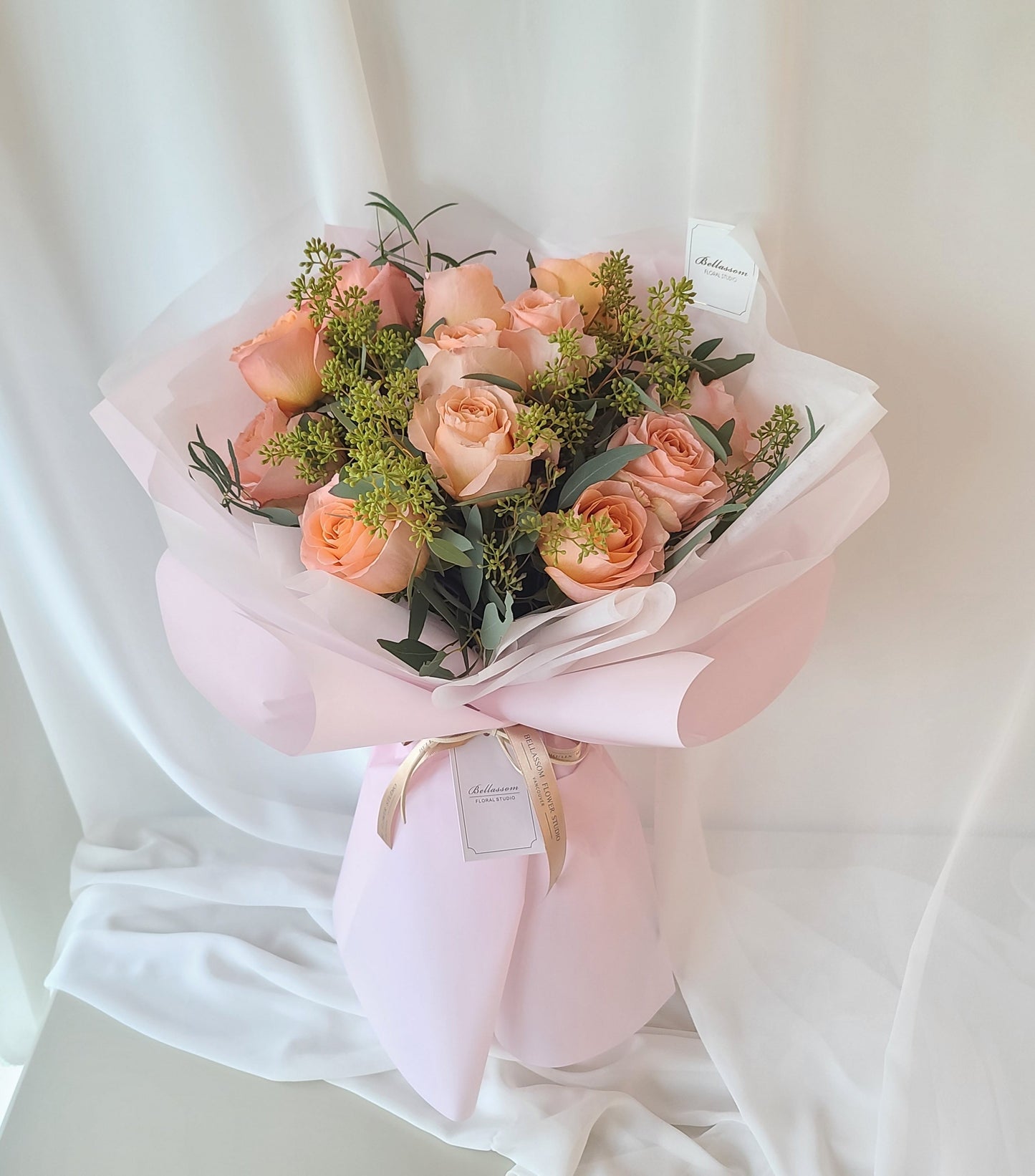 Dozen peach roses with fresh eucalyptus greenery arranged in a soft romantic bouquet, perfect for birthdays or elegant gifting, Vancouver delivery or Metrotown pick-up
